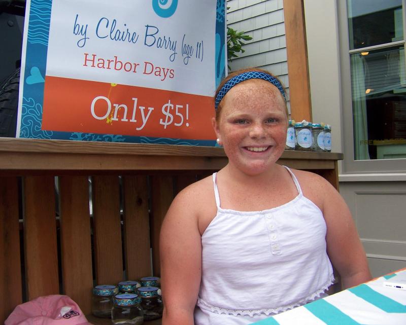 Claire Berry, 12, of Mattapoisett sells jars holding local rocks, sand and seawater at Harbor Days. BY MATTHEW BERNAT